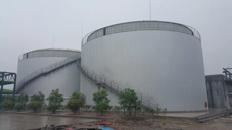 Large anaerobic treatment tanks with access stairs and surrounding landscaping